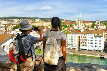 Two female tourists taking photos at Limmatquai in Zurich, Switzerland.