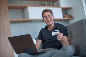 young man using Bank card in his living room.