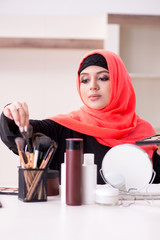 Beautiful woman in hijab applying make-up