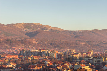 Golden hour view of Pirot cityscape, and impressive, rocky, sunlit summit above the city