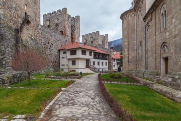 Fototapeta na wymiar Beautiful backyard and park inside the fortress walls on Manasija monastery. green grass, defensive towers and rocky pavement