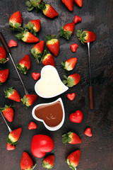 Valentine Chocolate fondue melted with fresh strawberries and dark and white chocolate. Red roses and sugar hearts for Valentines Day. Valentine Background