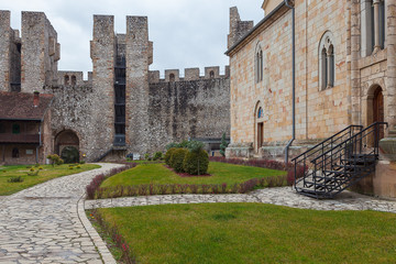 Fototapeta na wymiar Beautiful backyard and park inside the fortress walls on Manasija monastery. green grass, defensive towers and rocky pavement