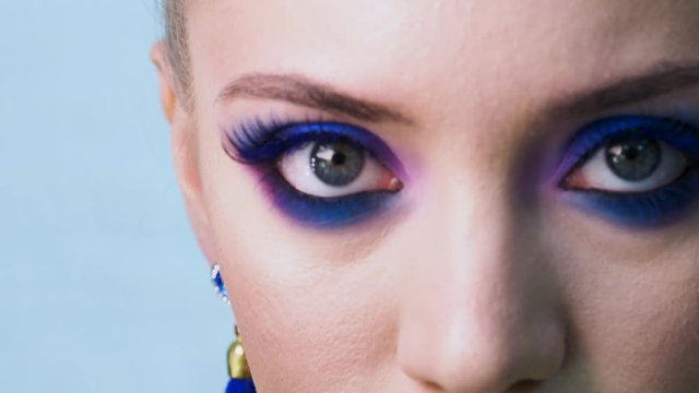 Glamorous bright eye makeup, women's eyes close-up. Bright party makeup, eye shadow and arrow eyeliner, trending color classic blue