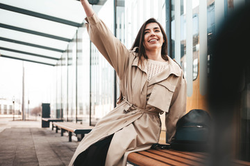 Obraz premium Positive young woman sitting at a public transport stop and waving