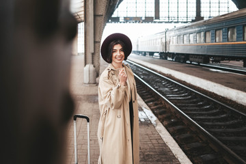 Beautiful stylish woman traveler stands on the peron of the station waiting for the train