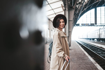 Obraz premium Beautiful stylish woman traveler stands on the peron of the station waiting for the train