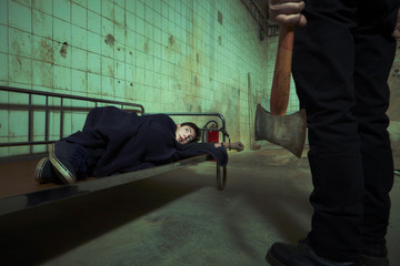 Evil kidnapper holding and controlling young man in horror place