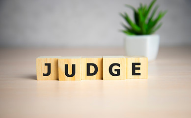 Letter block in word judge on wooden cubes on table.