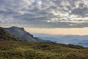 Stunning view from Old mountain highlands on mountain layers in Bulgaria with foreground juniper and colorful sunrise sky