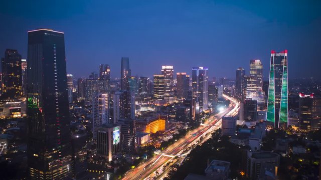 JAKARTA, Indonesia - January 28, 2020: Beautiful aerial time lapse of light trails on highway with skyscrapers at night time in Jakarta city. Shot in 4k resolution