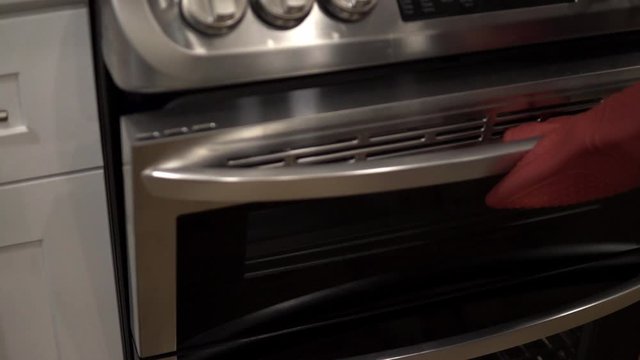 A young girl puts a baking pan into the oven with crust for making millionaire shortbread cookies