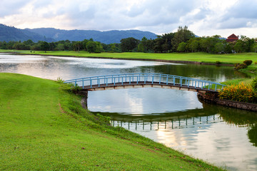 small bridge in golf course green grass field and lagoon.