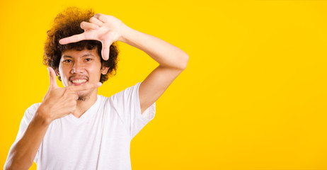 Asian handsome man with curly hair he smiling making frame with hands and fingers with happy face for creativity photography