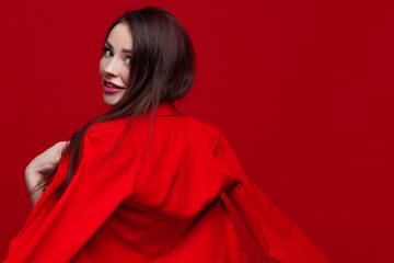 Naklejka premium Bright and beautiful girl in a red pantsuit on a red background