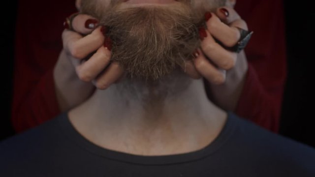 Hands of woman massaging man's beard, slow motion, shallow depth of field