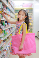 Attractive little asian girl carrying a pink recycle bag (spun ball bag) while go to retail stores....