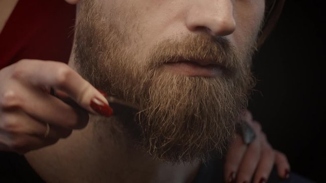 Woman combing beard of man, shallow depth of field, slow motion