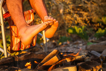 Man warms his bare feet over the fire