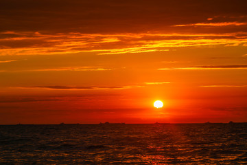 Merchant ships on the horizon against the background of a fiery red sunset