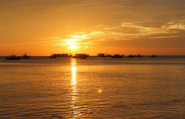 Fototapeta na wymiar Fishing boats at a deserted beach on a sunset background