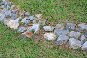 Small wall fence made from Rock Stone in grass garden background.