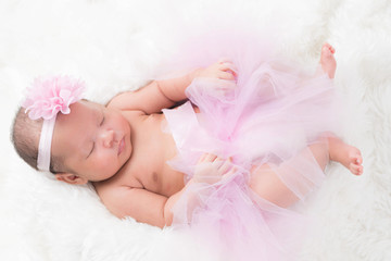 Cute newborn baby lies swaddled in a white blanket. Close up view.