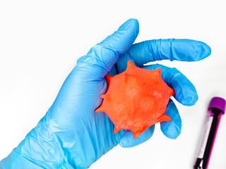 a gloved hand of a medical worker holds a virus-shaped balloon with a test tube on the background