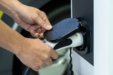 Male Hand holding electric charging of car