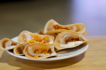 Thai crispy pancake on wood plate with space for write wording , popular sweet street snack sold in market and restaurant, unhealthy food contain high sugar, fat and fat cause of many chronic diseases