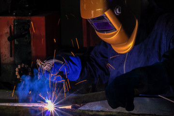 A craftman is welding with workpiece steel.Working person About welder steel Using electric welding machine There are lines of light coming out and safety equipment in factory industry..