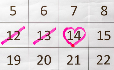 Female Hand with pen mark heart shape on calendar date at 14th valentine day
