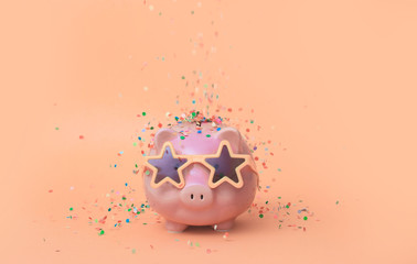 A pink piggy bank in fun glasses at a party. pink background.