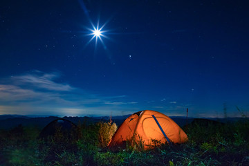 Orange tent lit under the starry sky. Camping tent under the night sky.