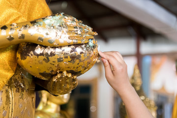 Hands attached to the gold leaf of the Buddha.