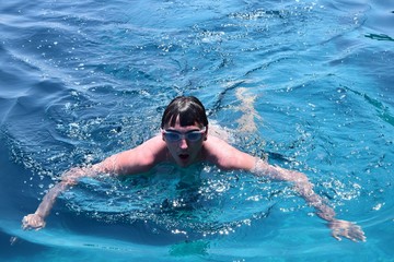 Fototapeta premium young man swimming in blue water portrait 