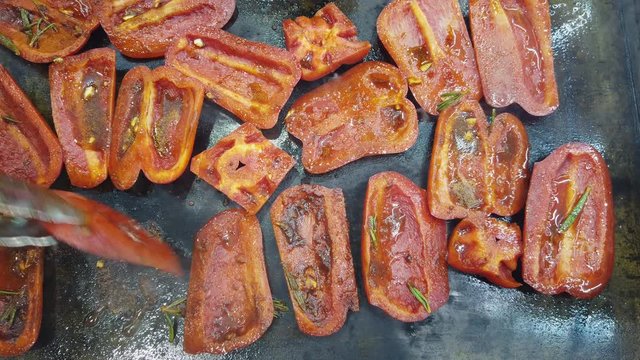 Slices of red bell pepper are fried on a hot plate. Roasting vegetables.