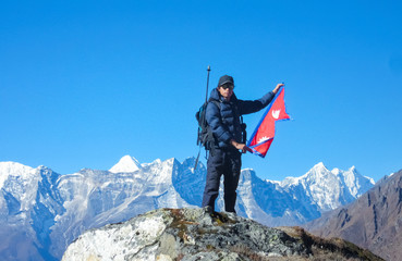Guy holding National Flag of Nepal against Himalaya Mountain Peak. 