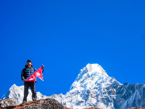 Guy holding National Flag of Nepal against Himalaya Mountain Peak. 
