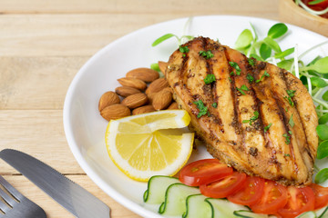 Top view of Fresh salad with chicken breast in white dish on wooden table, Almond,Sunflower seedling,Cucumber,Tomato,Lemon.