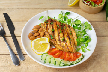 Top view of Fresh salad with chicken breast in white dish on wooden table, Almond,Sunflower seedling,Cucumber,Tomato,Lemon.