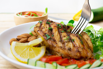 Top view of Fresh salad with chicken breast in white dish on wooden table, Almond,Sunflower seedling,Cucumber,Tomato,Lemon.