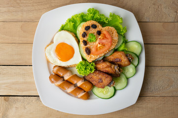 American fried rice with cucumber and lettuce in white dish on wooden table.