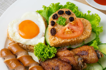 American fried rice with cucumber and lettuce in white dish on wooden table.