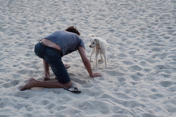 young man playing with stray dog on the beach