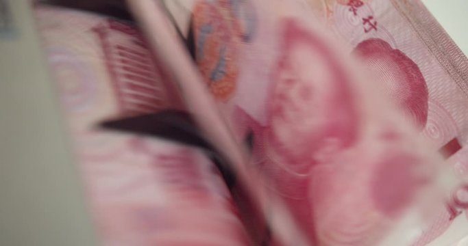 Closeup of electronic or automatic machine for counting bills or money. Banknote or currency counter counts one hundred / 100 CNY Chinese yuan cash, banking and commercial activity, financial concept.