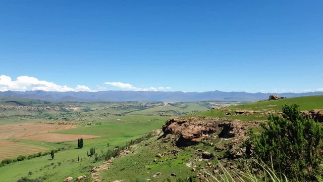 Maloti mountain range and farms in Free-state province near Clarens town and the Lesotho border. Roadside grass and flowers moving in the wind.