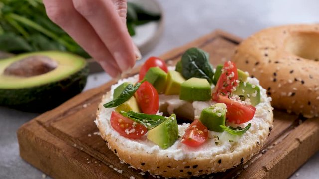 Seasoning healthy avocado toast with hemp seeds. Closeup view. Healthy breakfast or snack food