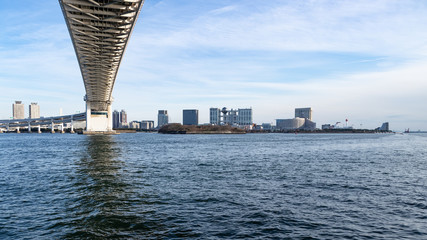 青空を背景に芝浦ふ頭側レインボーブリッジ下から見たお台場ビル群
