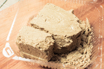 Large piece of fresh halva in transparent package on wooden board.